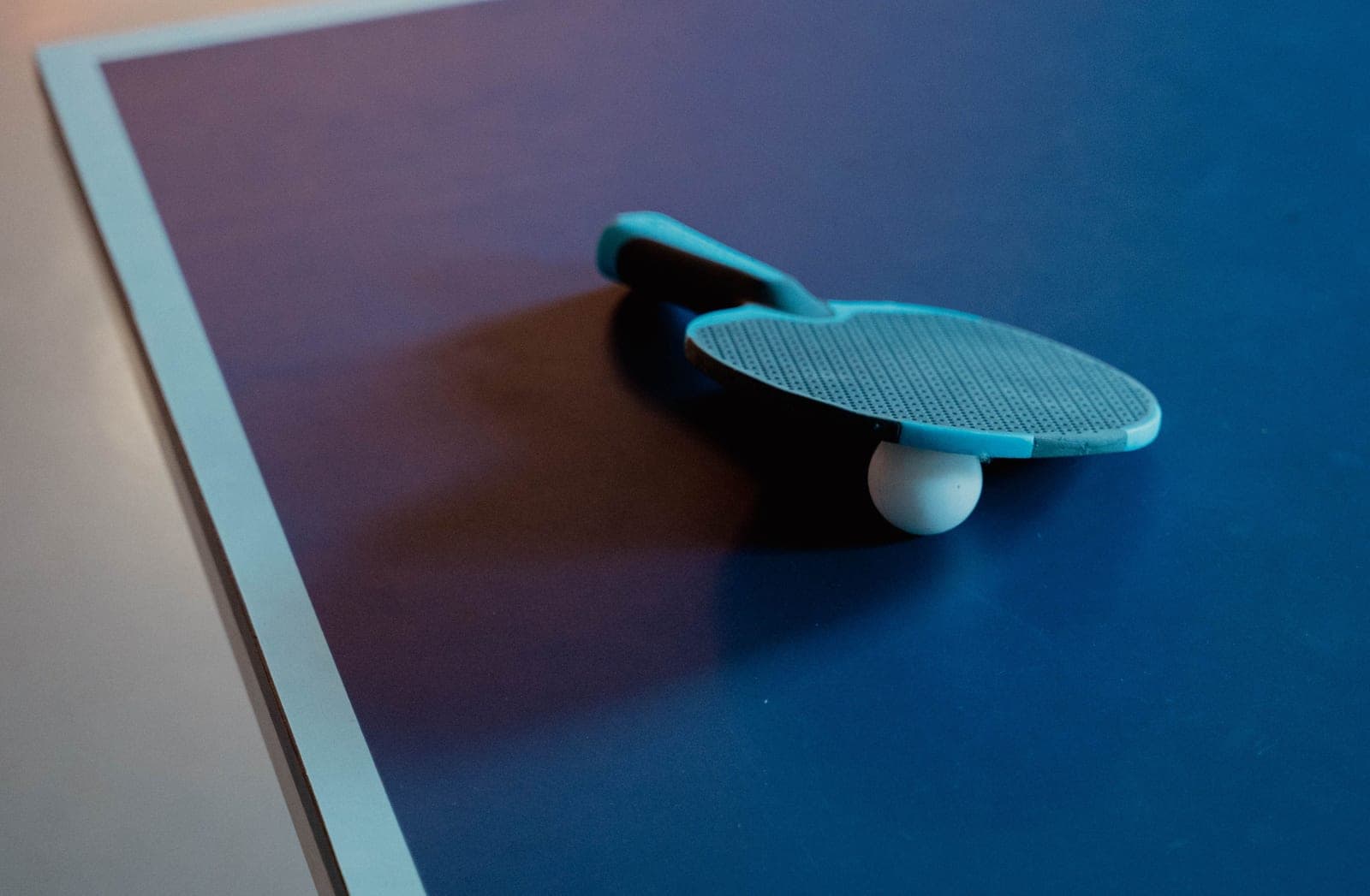 A full-size indoor table tennis table standing open in a basement with clear floor space at both ends