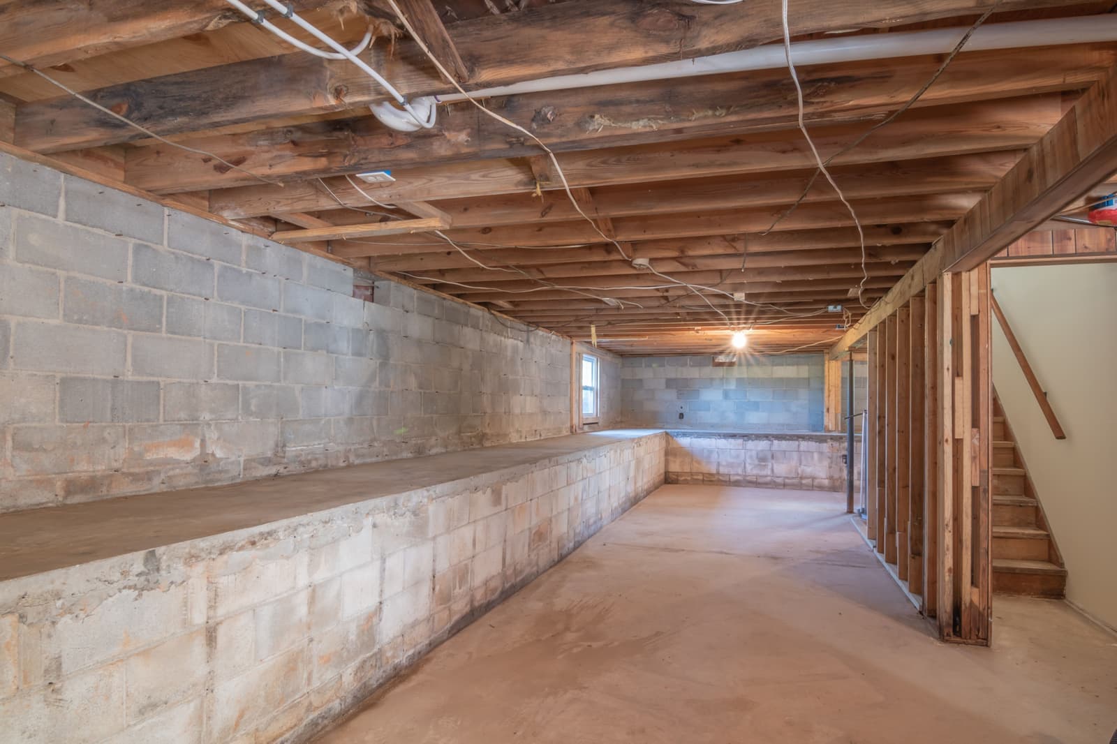 An empty unfinished basement with a support post and a concrete floor, waiting to be measured