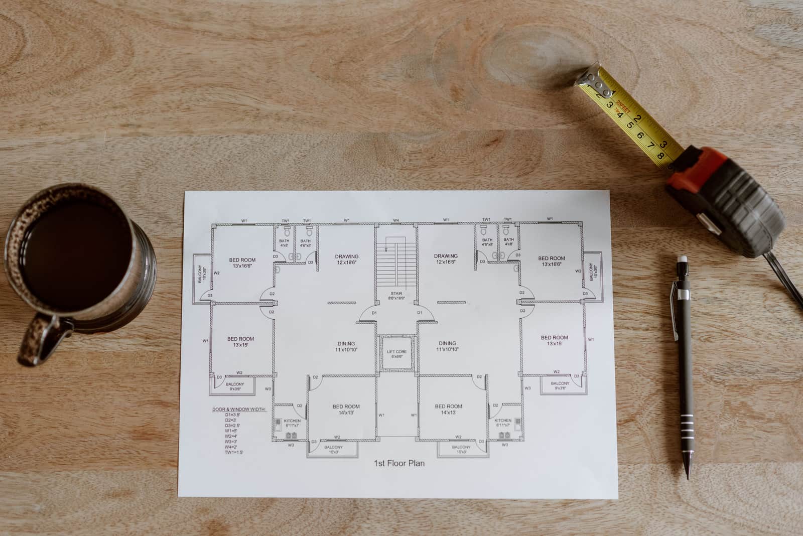 A tape measure stretched across a bare floor next to a hand-drawn room plan