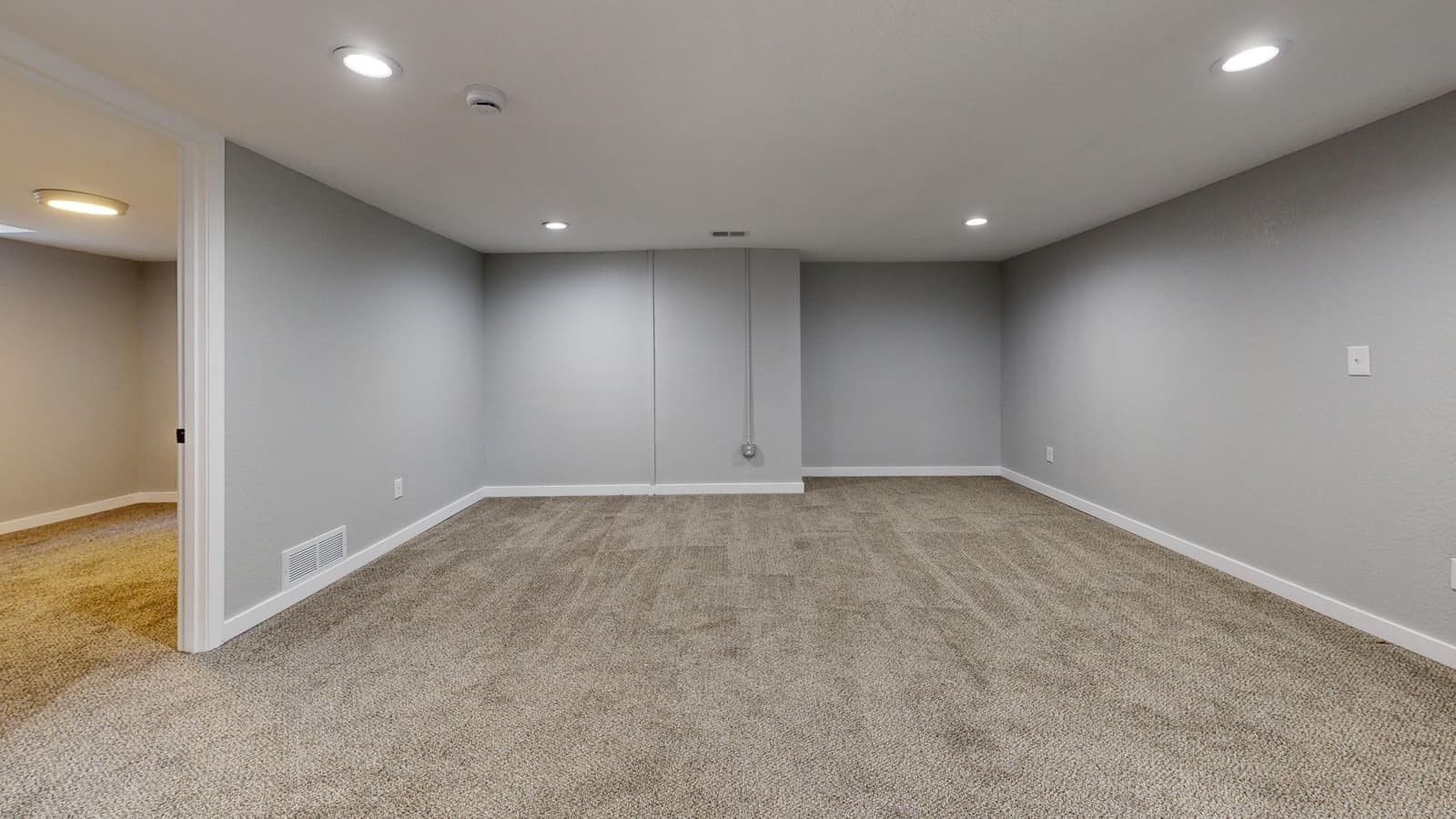 A finished basement recreation space with clear floor along one wall